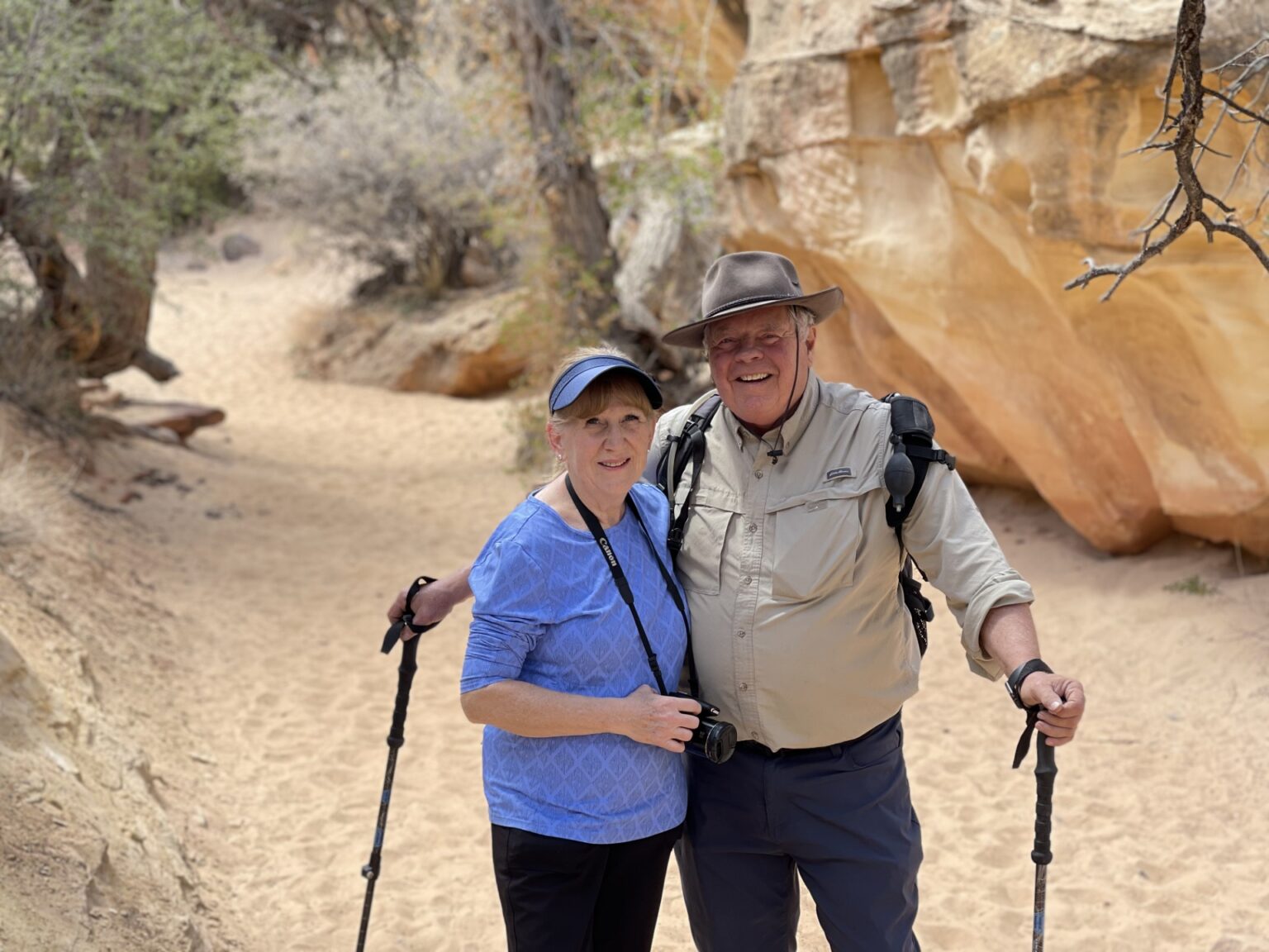 Older couple smiling together while hiking on a scenic sandstone trail.